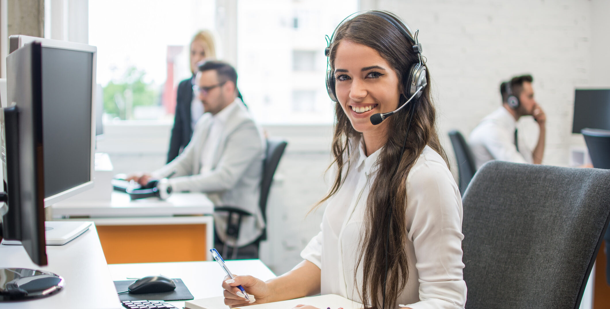 portrait of beautiful and cheerful young woman telephone operator agent with headset working in office
