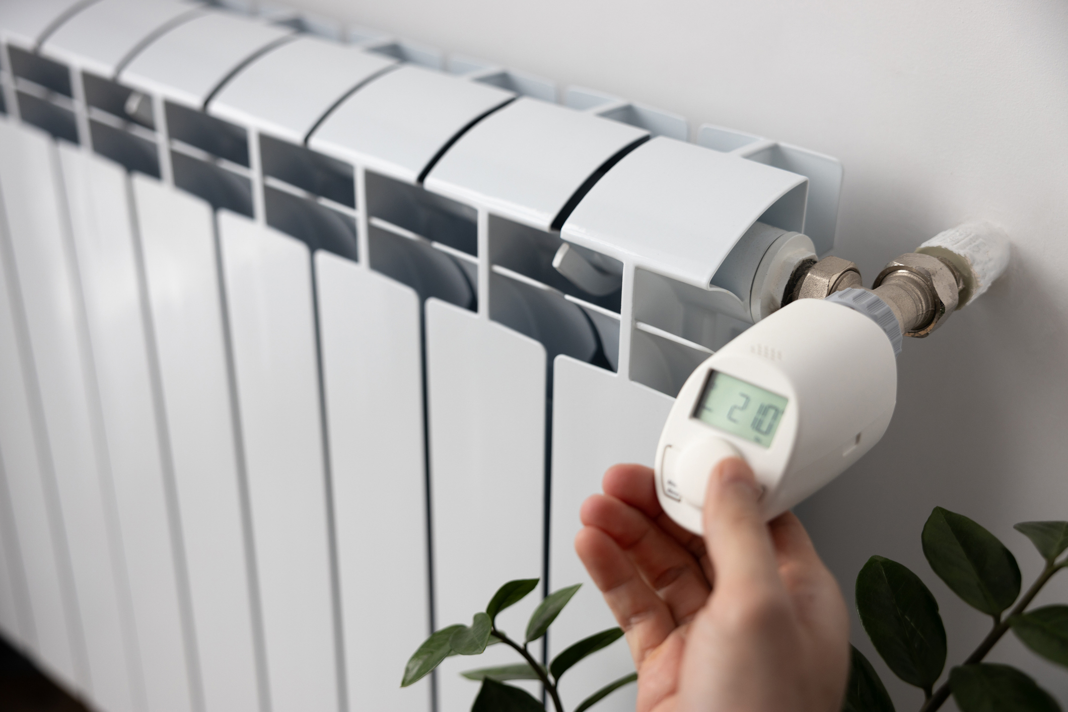 person sets the heating temperature on an electronic thermostat with his hand.