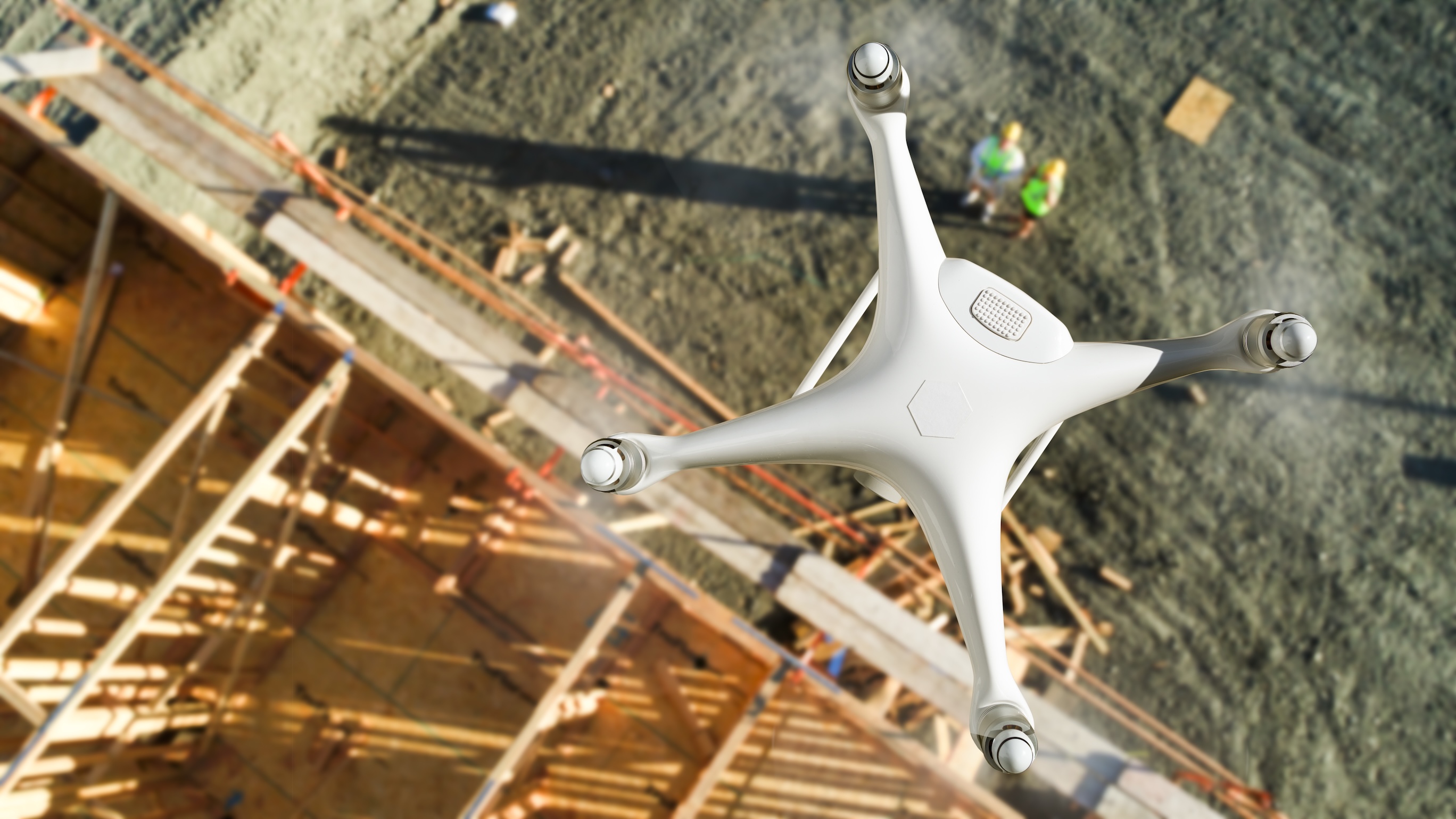 unmanned aircraft system (uav) quadcopter drone in the air above construction site.