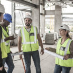 woman in protective workwear and construction workers in construction site