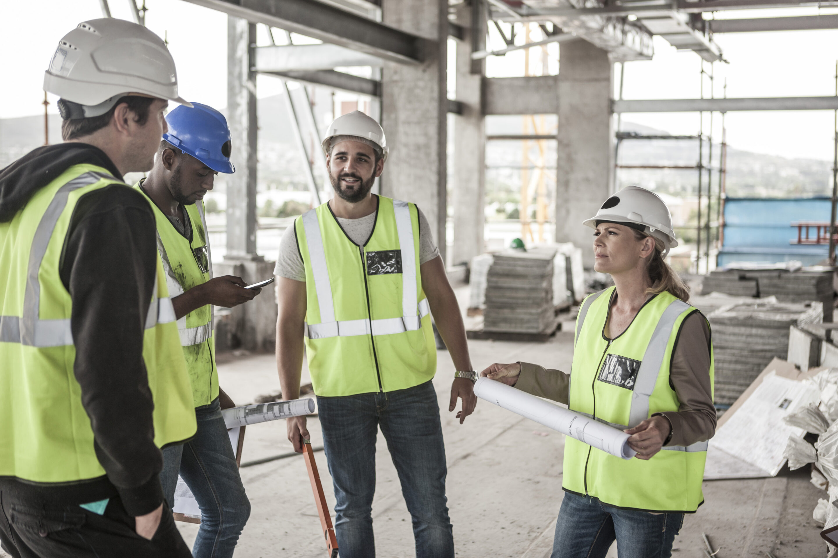 woman in protective workwear and construction workers in construction site