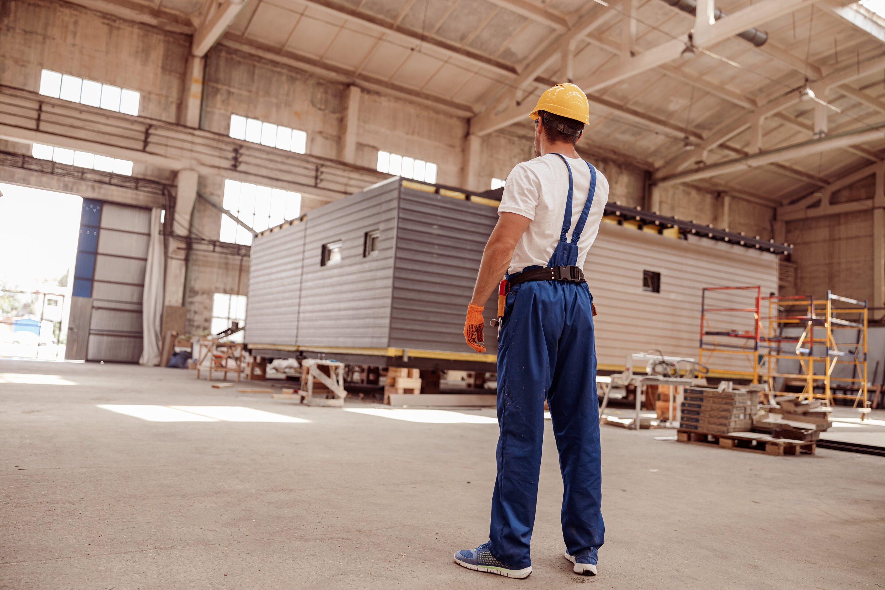 male builder standing inside building with construction cabin