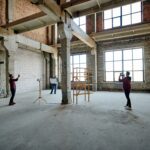 two young contractors photographing unfinished structure inside building