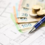 european union euro money bills and coins with construction project blueprints on table