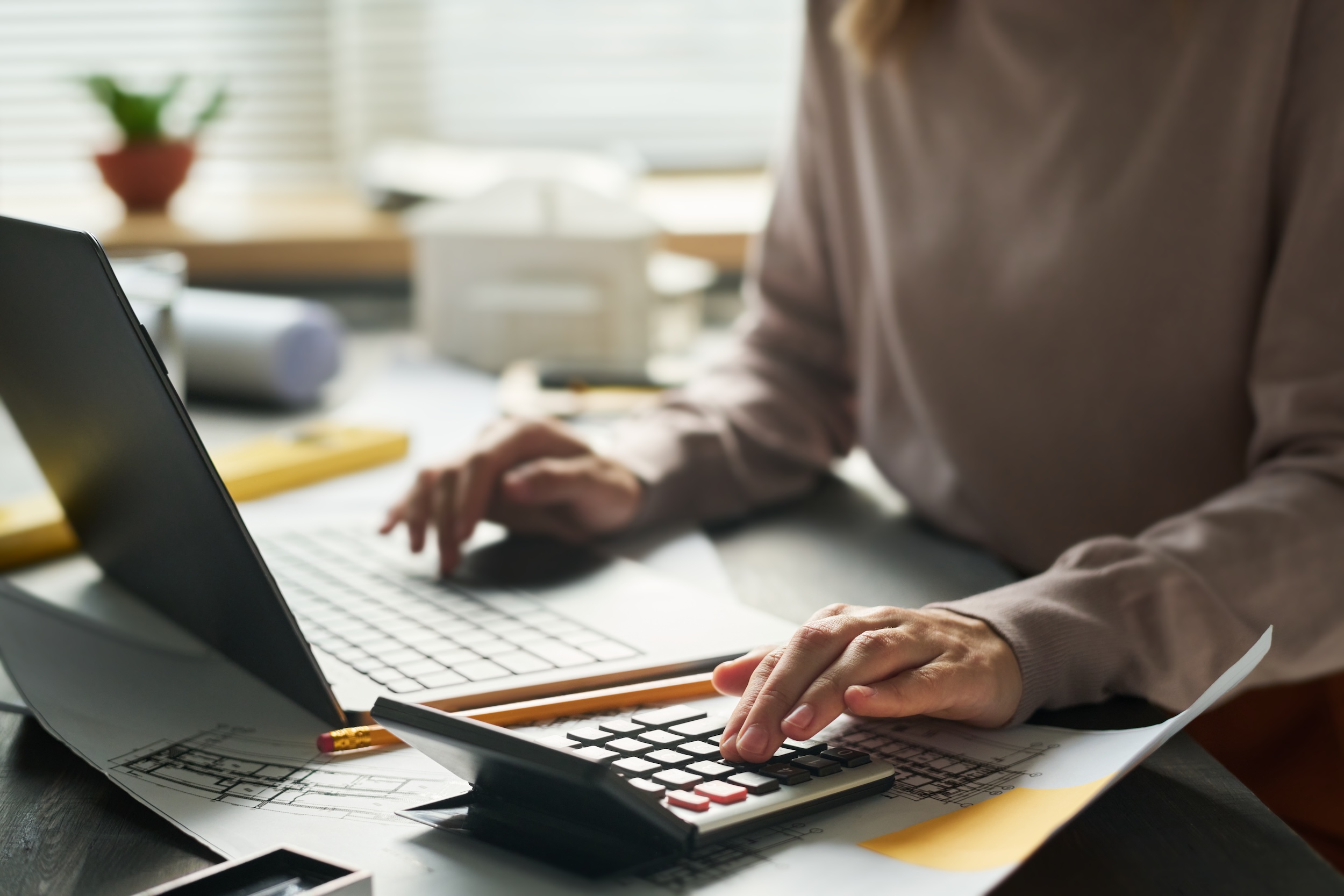 focus on hand of young female architect pressing buttons of calculator