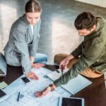 high angle view of businessman showing something at blueprint to businesswoman
