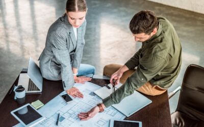 high angle view of businessman showing something at blueprint to businesswoman