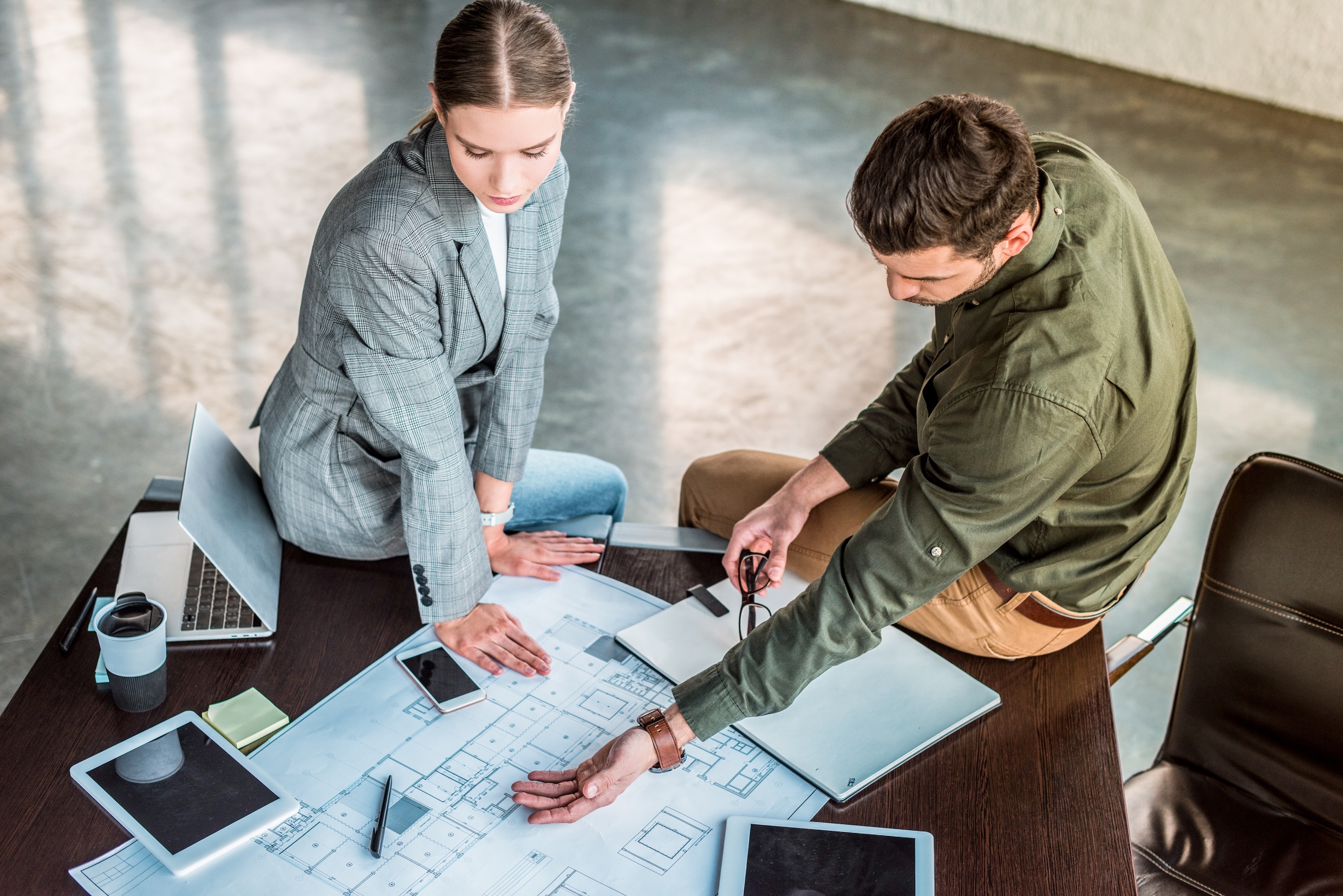high angle view of businessman showing something at blueprint to businesswoman