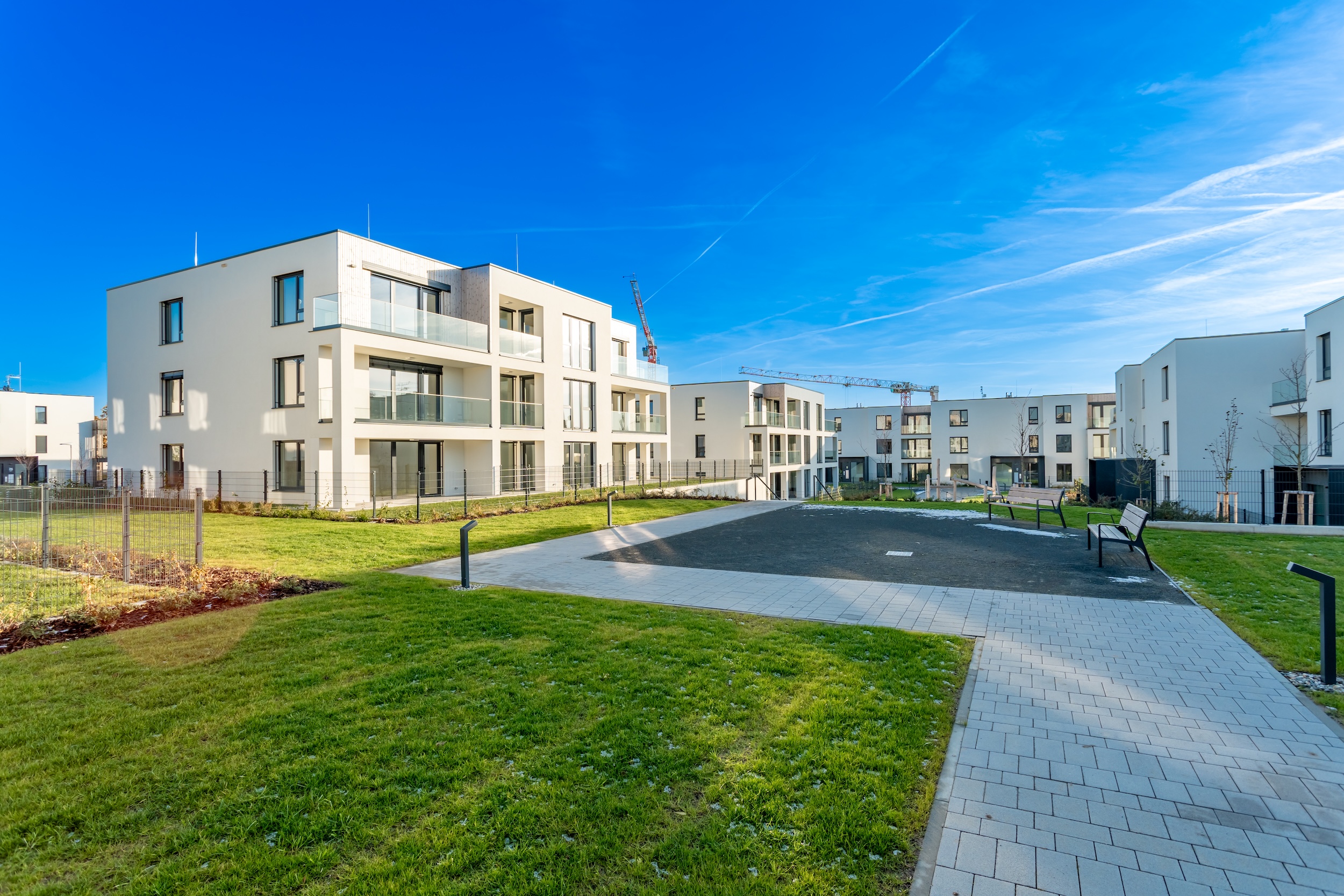 modern residential complex with green areas and construction crane on sunny day