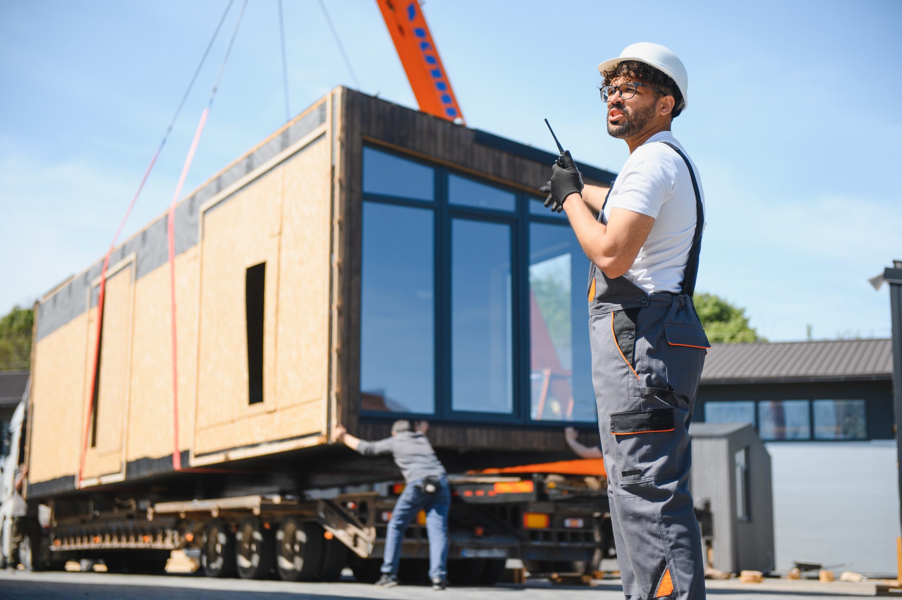 construction worker supervising loading of modular house onto truck