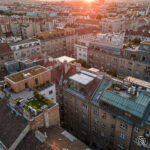 Luftaufnahme eines dicht bebauten europäischen Stadtviertels mit mehreren modernen Dachaufstockungen auf bestehenden Wohngebäuden bei Abendlicht. Dieses Bild wurde mithilfe von KI erstellt.